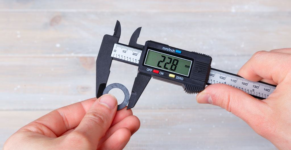 Différents joints industriels semi-métalliques et plats sur établi d'atelier avec pied à coulisse